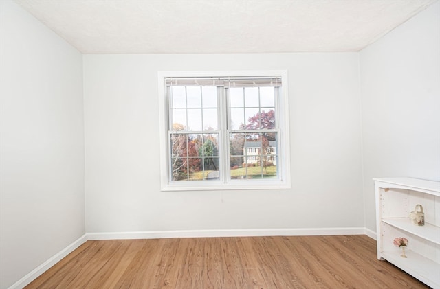 empty room with light hardwood / wood-style flooring and a textured ceiling