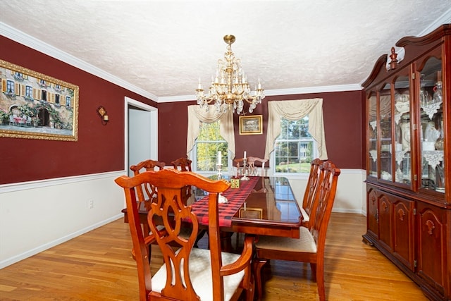 dining space with light hardwood / wood-style flooring, ornamental molding, and a notable chandelier