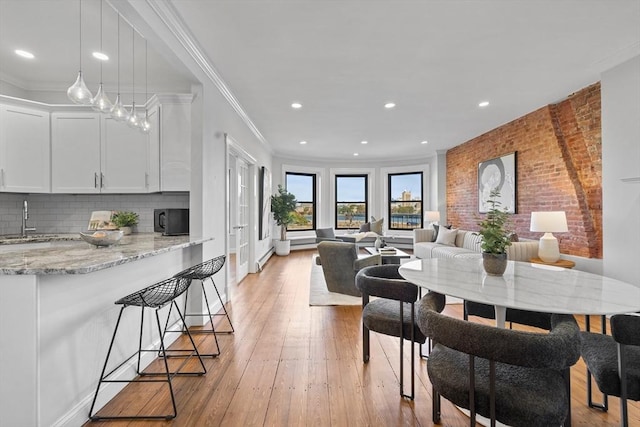 dining space featuring ornamental molding, recessed lighting, brick wall, and light wood finished floors