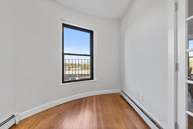 empty room featuring baseboards, baseboard heating, and wood finished floors