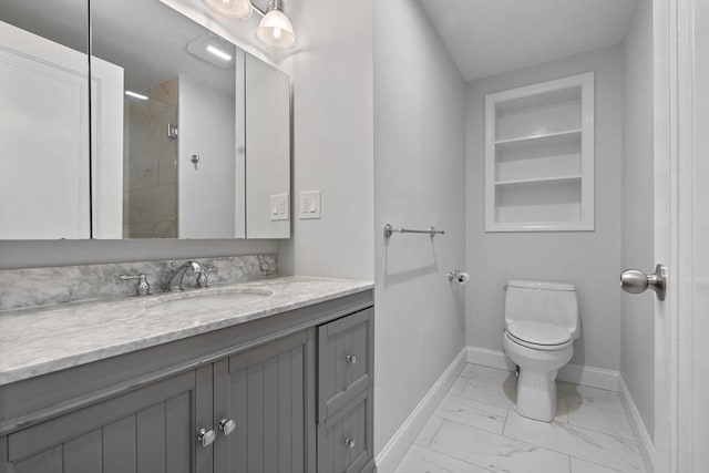 bathroom with toilet, vanity, baseboards, marble finish floor, and tiled shower