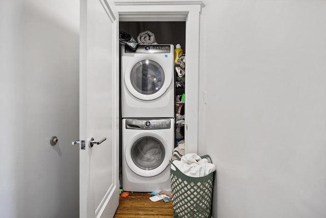 laundry room featuring laundry area, wood finished floors, and stacked washer and clothes dryer