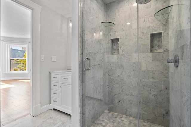 full bathroom with a shower stall, baseboards, and vanity