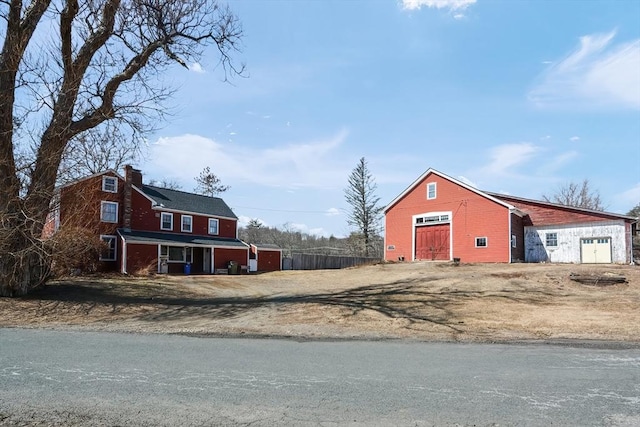 exterior space with a barn, an outdoor structure, dirt driveway, and fence