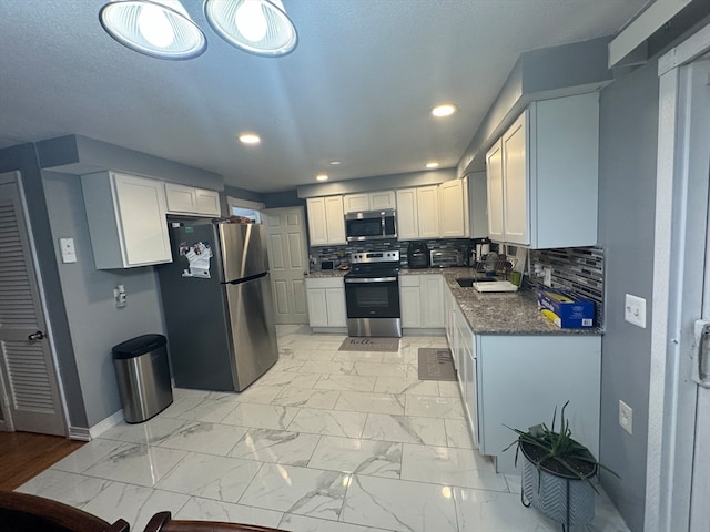 kitchen with dark stone counters, stainless steel appliances, white cabinetry, and tasteful backsplash