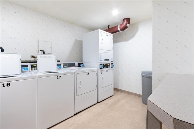 common laundry area with washing machine and dryer, wallpapered walls, stacked washing maching and dryer, and light carpet