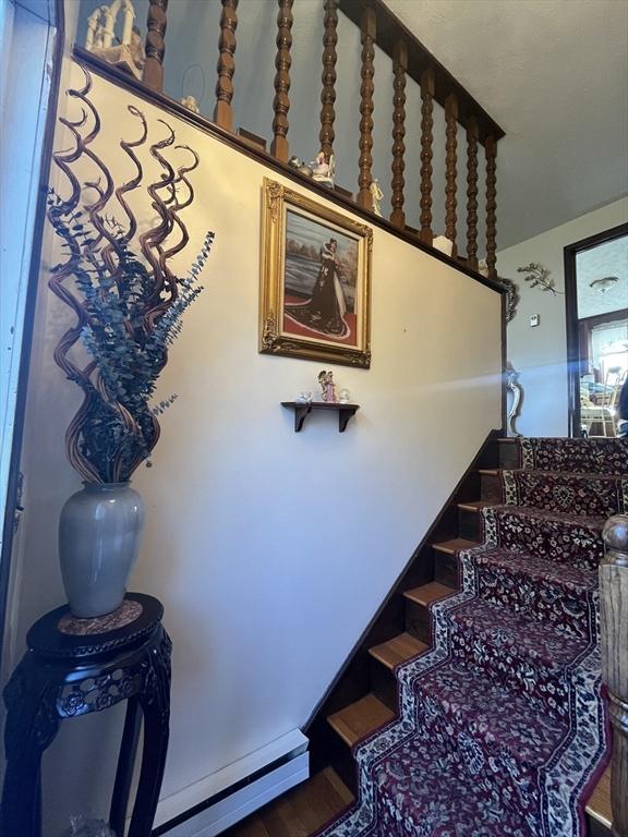 staircase with wood finished floors and baseboard heating