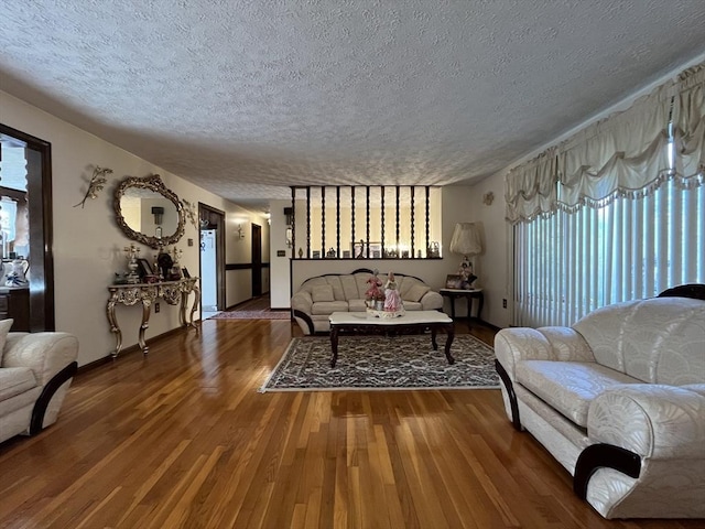 living area featuring baseboards, a textured ceiling, and wood finished floors