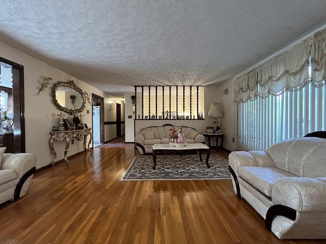 living area with baseboards, a textured ceiling, and wood finished floors