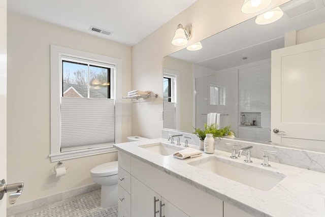 bathroom with toilet, a shower with door, visible vents, and a sink