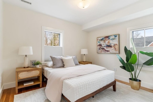 bedroom featuring wood finished floors, visible vents, and baseboards