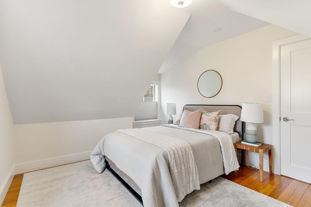 bedroom featuring vaulted ceiling, wood finished floors, and baseboards