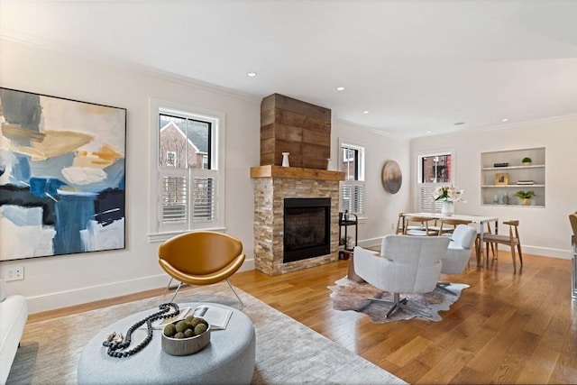 living area with built in shelves, hardwood / wood-style floors, and crown molding