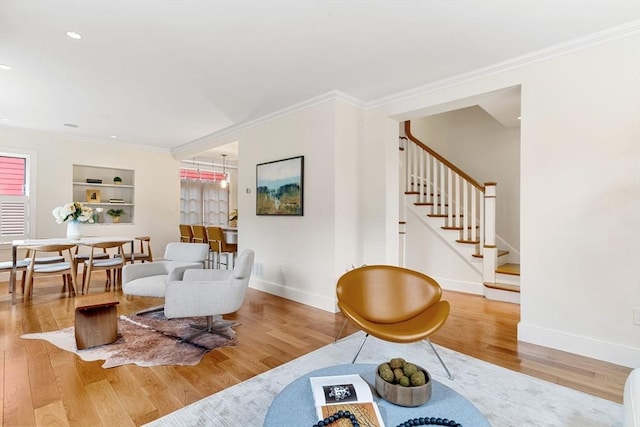 living room with crown molding, stairs, baseboards, and wood finished floors