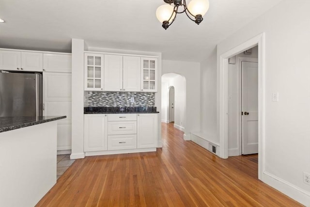 kitchen featuring stainless steel refrigerator, light hardwood / wood-style flooring, decorative backsplash, and white cabinets