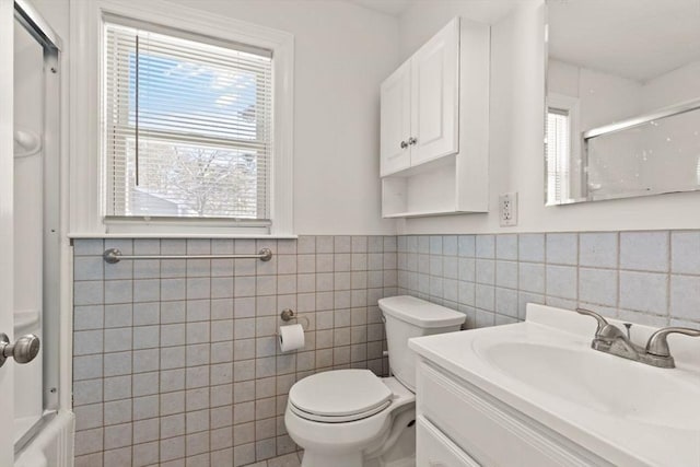 full bathroom featuring tile walls, vanity, combined bath / shower with glass door, and toilet