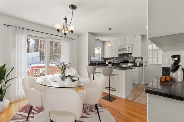 dining area featuring an inviting chandelier, sink, and light hardwood / wood-style flooring