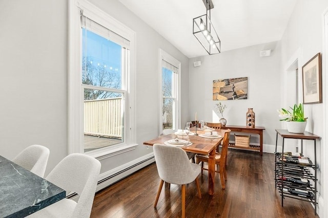 dining space with a baseboard heating unit, wood finished floors, and baseboards