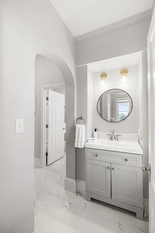 bathroom with baseboards, marble finish floor, ornamental molding, and vanity