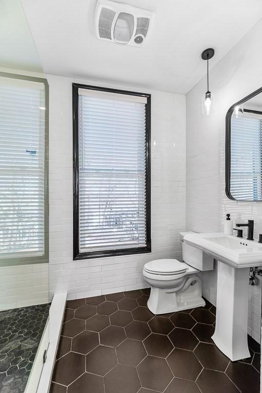 bathroom featuring tile patterned flooring, visible vents, a healthy amount of sunlight, toilet, and tile walls