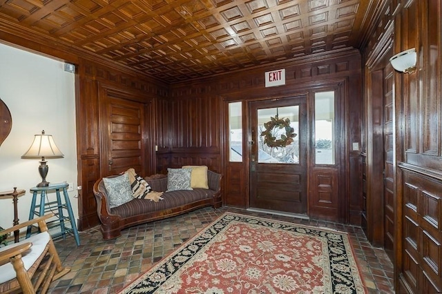 foyer featuring an ornate ceiling, wooden walls, and ornamental molding