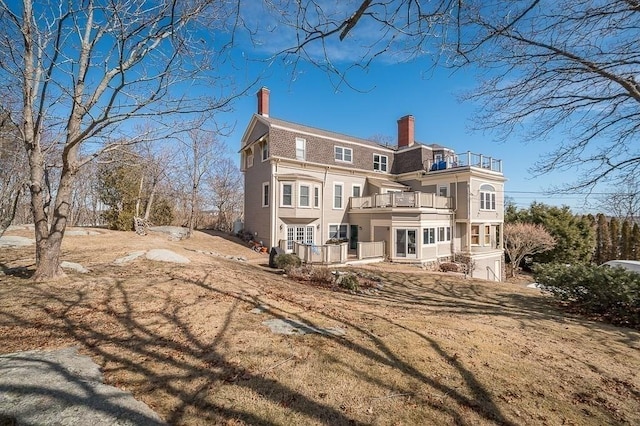 back of property featuring a chimney and a balcony