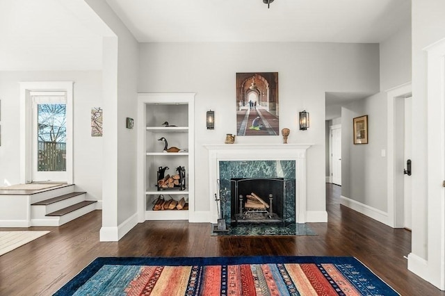 unfurnished living room with built in features, baseboards, wood finished floors, and a fireplace