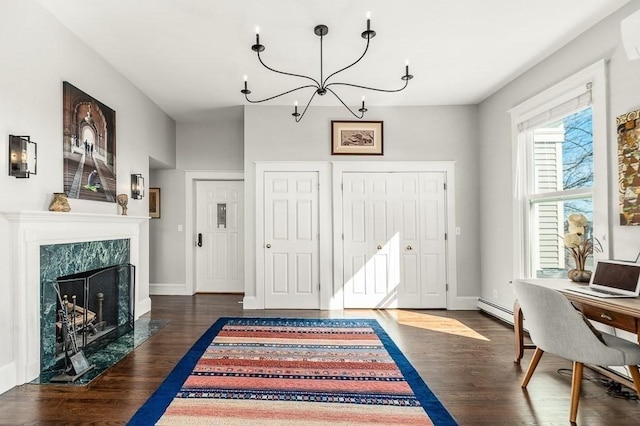 foyer entrance with a high end fireplace, baseboards, a chandelier, baseboard heating, and wood finished floors