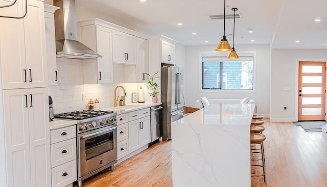 kitchen featuring wall chimney range hood, tasteful backsplash, a breakfast bar area, premium appliances, and a center island