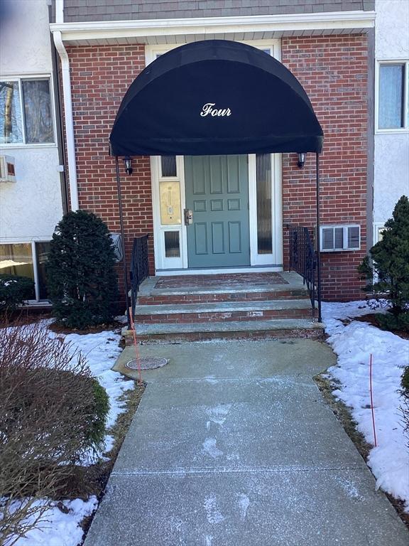 snow covered property entrance featuring brick siding