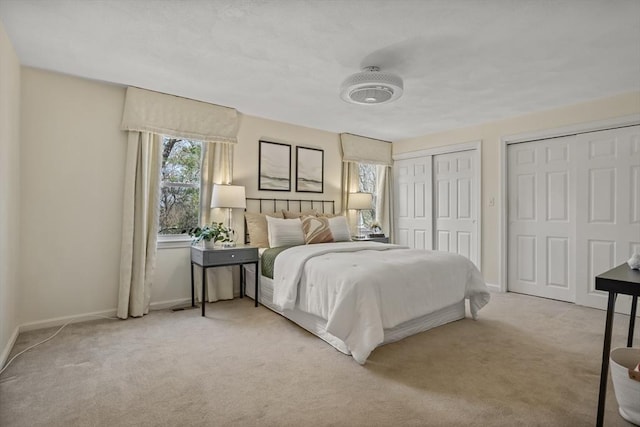 bedroom featuring carpet floors, multiple closets, and baseboards