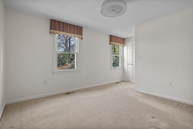 unfurnished room with baseboards, light carpet, and visible vents