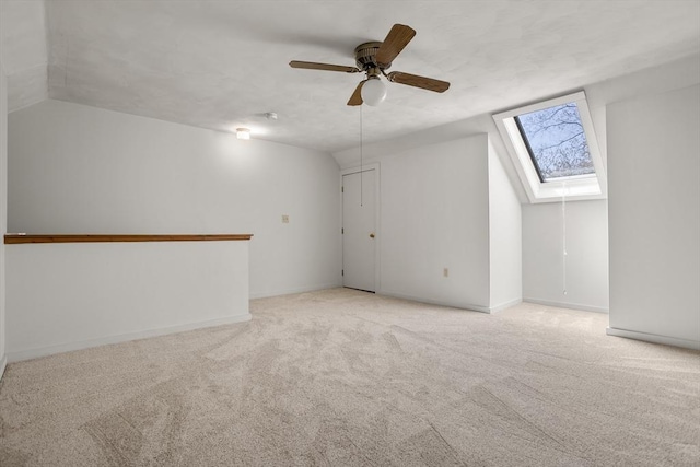 bonus room with baseboards, carpet, lofted ceiling with skylight, and ceiling fan