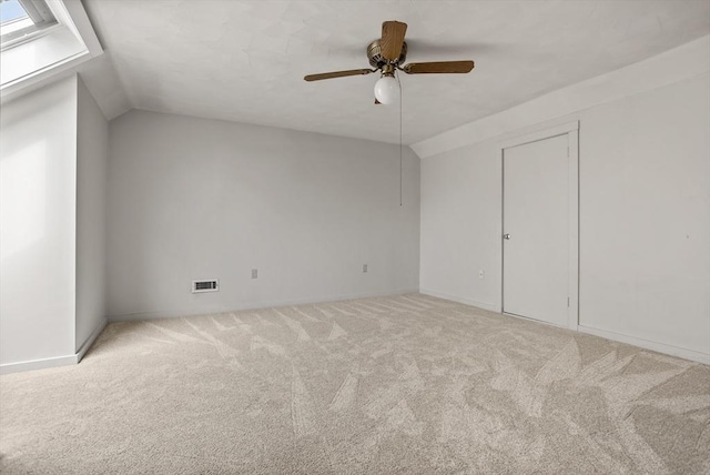carpeted spare room featuring visible vents, baseboards, ceiling fan, and vaulted ceiling