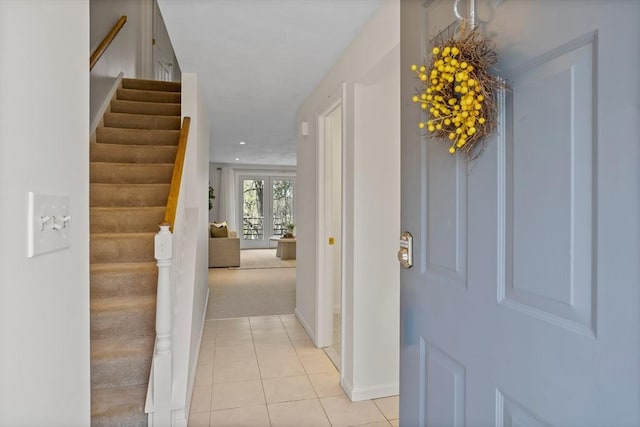 hall with baseboards, light carpet, light tile patterned flooring, and stairway