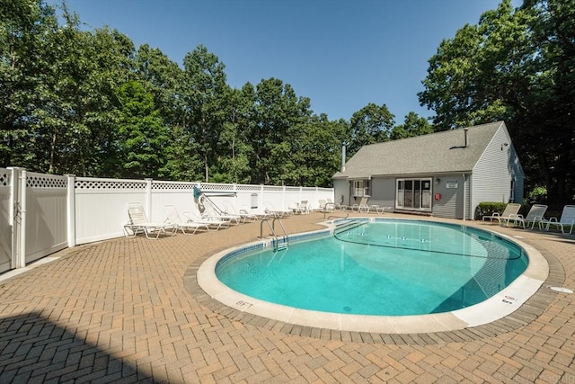 community pool with a patio area and fence