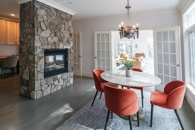 dining area with dark wood-style flooring, a fireplace, an inviting chandelier, ornamental molding, and baseboards