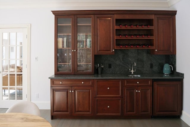 bar featuring tasteful backsplash, wet bar, light wood-style floors, and a sink