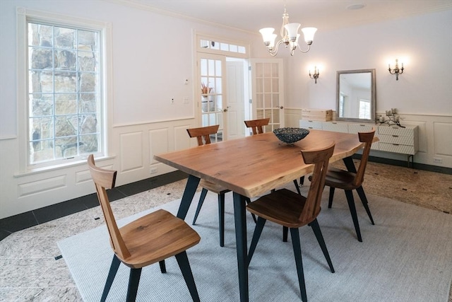 tiled dining room with a wainscoted wall, plenty of natural light, and a decorative wall