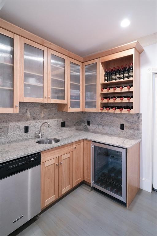 bar featuring decorative backsplash, wine cooler, dishwasher, and a sink