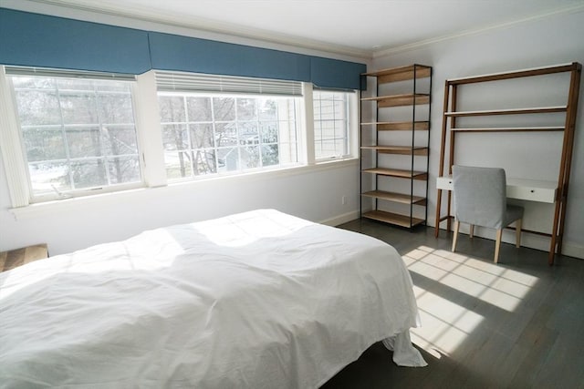 bedroom with ornamental molding, baseboards, and wood finished floors