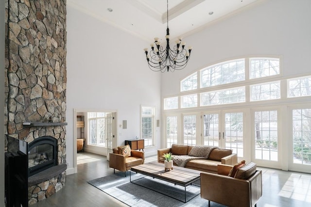 living area with a towering ceiling, an inviting chandelier, a fireplace, and wood finished floors