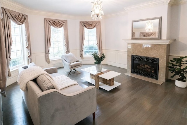 living room featuring ornamental molding, a premium fireplace, wood finished floors, and an inviting chandelier