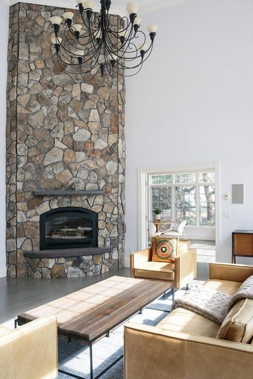 living area with a chandelier, a fireplace, and a towering ceiling