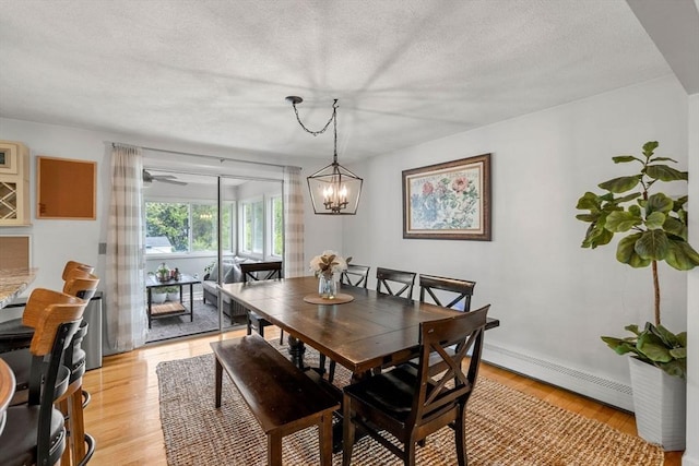 9 Indian Rock Dr, Saugus, MA 01906 - dining space with a baseboard heating unit, light wood finished floors, a chandelier, baseboards, and a textured ceiling