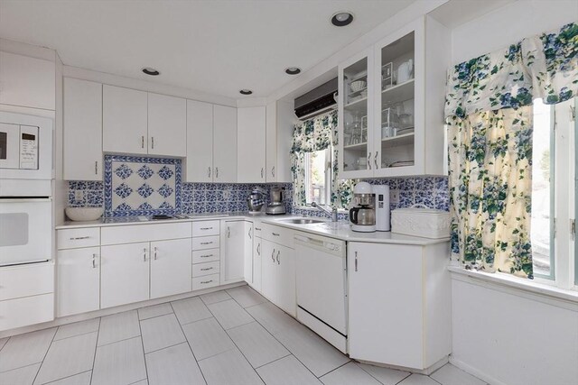 kitchen with white appliances, tasteful backsplash, a sink, and light countertops