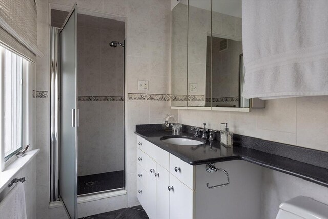 full bathroom featuring vanity, tile walls, and a shower stall