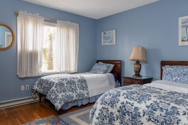 bedroom with baseboard heating and wood finished floors