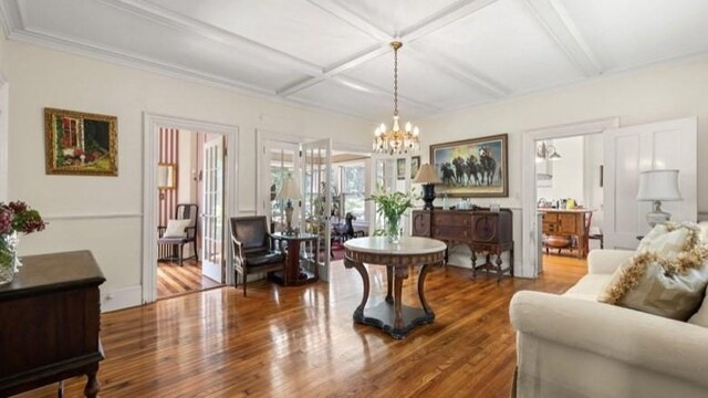 living room featuring a notable chandelier, coffered ceiling, and hardwood / wood-style flooring