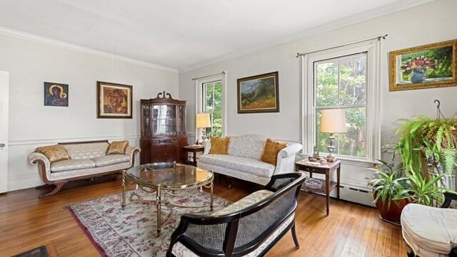 living room featuring baseboard heating, hardwood / wood-style flooring, plenty of natural light, and ornamental molding